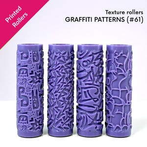 May include: Four purple texture rollers with graffiti patterns. The rollers are cylindrical and feature various raised designs, including geometric shapes and abstract patterns. The text "Printed Rollers" and "GRAFFITI PATTERNS (#61)" are visible.