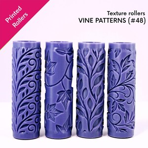 May include: Four purple texture rollers with vine patterns. The rollers are cylindrical and feature detailed leaf and floral designs. The text "Printed Rollers" is in the upper left corner, and "VINE PATTERNS (#48)" is displayed.