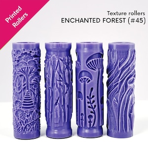 May include: Four purple texture rollers with various designs, including mushrooms, trees, and organic patterns. The rollers are cylindrical and feature the text "ENCHANTED FOREST (#45)" and "Printed Rollers".