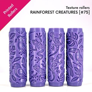 Pode incluir: Quatro rolos de textura cilíndricos roxos com desenhos em relevo de criaturas da floresta tropical, incluindo papagaios, sapos, lagartos e tucanos entre folhas. O texto diz: Printed Rollers, Texture rollers, RAINFOREST CREATURES [#75].