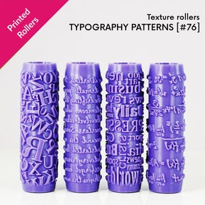 Könnte beinhalten: Vier lila Texturwalzen mit Typografiemustern. Die zylindrischen Walzen weisen verschiedene Designs auf, darunter Buchstaben, Schrift und mathematische Symbole. Der Text "Printed Rollers" und "Typography Patterns [#76]" ist sichtbar.