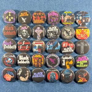 May include: A collection of 30 black Black Sabbath band button pins. Each pin features a different design, including album art, band logos, and the band's name. The pins are round and have a glossy finish.