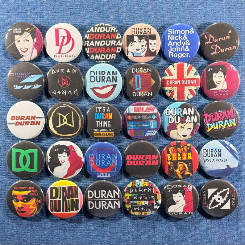 Puede incluir: Colecci&oacute;n de botones redondos de Duran Duran, de aproximadamente 2,5 cm de di&aacute;metro. Los botones presentan varios dise&ntilde;os, incluyendo retratos de miembros de la banda, logotipos y arte de &aacute;lbumes. Los colores incluyen rojo, blanco, negro, azul y amarillo. El texto incluye t&iacute;tulos de canciones y el nombre de la banda.