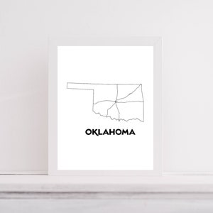 May include: A framed print featuring a minimalist black and white outline of the state of Oklahoma. The state's shape is clearly defined with internal roads and the word "OKLAHOMA" in bold, black text below the map.