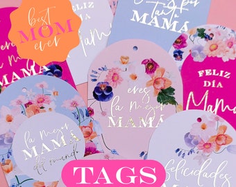 May include: A set of colorful gift tags with floral designs and gold lettering. The tags feature phrases like "Best Mom Ever", "Feliz Día Mama", and "Felicidades Mama".