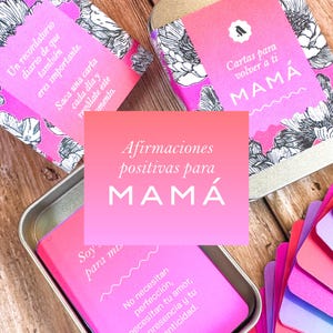 Puede incluir: Un conjunto de tarjetas rosas y blancas con motivos florales y una caja de metal. Las tarjetas tienen texto en español, incluyendo "Afirmaciones positivas para MAMÁ" y "Cartas para volver a ti MAMÁ".
