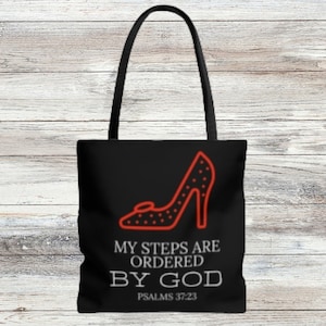 Op de afbeelding: Zwarte tote bag met een rode high-heel schoen afbeelding en de tekst "Mijn stappen zijn geordend door God, Psalm 37:23".