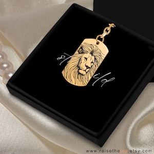 Può includere: Portachiavi dorato con una testa di leone incisa su un ciondolo a forma di targhetta. Il ciondolo ha un contorno nero e la criniera del leone è dettagliata. Il portachiavi è in una scatola nera con le parole "stay wild" scritte su di essa.