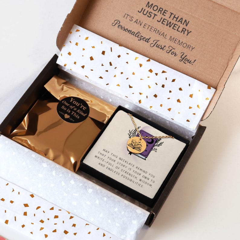 Pu&ograve; includere: Una collana dorata con un ciondolo rotondo raffigurante un libro, presentata in una confezione regalo. La scatola contiene un sacchetto di lamina d'oro e una carta con testo motivazionale. La scatola &egrave; marrone con coriandoli bianchi.