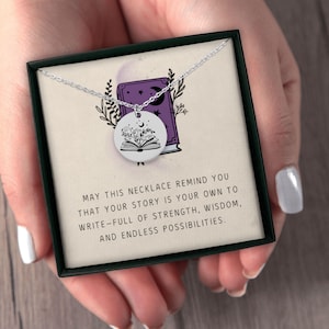 Pu&ograve; includere: Una collana d'argento con un ciondolo rotondo raffigurante un libro aperto con motivi floreali e celesti. La collana &egrave; presentata in una scatola nera con il testo: "MAY THIS NECKLACE REMIND YOU THAT YOUR STORY IS YOUR OWN TO WRITE-FULL OF STRENGTH, WISDOM, AND ENDLESS POSSIBILITIES."