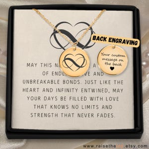 May include: Gold necklace with a circular pendant showing an infinity heart design. The necklace is presented in a black box with a message about unbreakable bonds. The back of the pendant is engravable.
