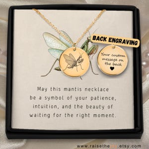 Puede incluir: Collar dorado con dos colgantes redondos. Uno muestra una mantis religiosa, el otro tiene espacio para un mensaje personalizado. El texto dice: "Que este collar de mantis sea un símbolo de tu paciencia..."