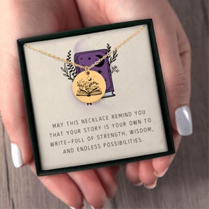 Pu&ograve; includere: Una collana color oro con un ciondolo rotondo con un design a libro aperto con dettagli floreali e lunari. La collana &egrave; presentata in una scatola nera con il testo: "MAY THIS NECKLACE REMIND YOU THAT YOUR STORY IS YOUR OWN..."