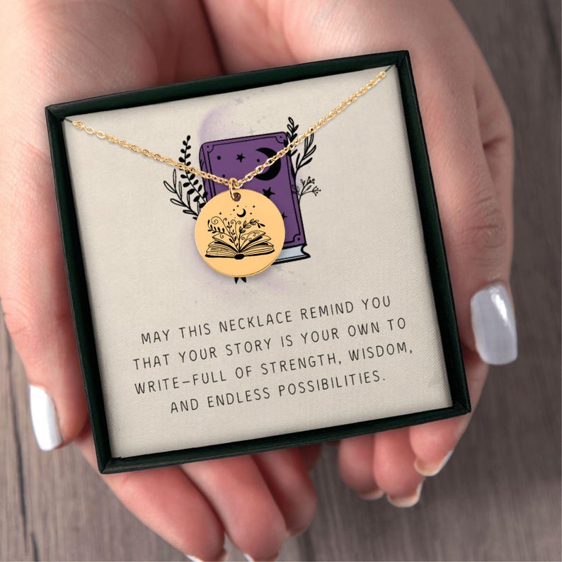 Pu&ograve; includere: Una collana color oro con un ciondolo rotondo con un design a libro aperto con dettagli floreali e lunari. La collana &egrave; presentata in una scatola nera con il testo: "MAY THIS NECKLACE REMIND YOU THAT YOUR STORY IS YOUR OWN..."