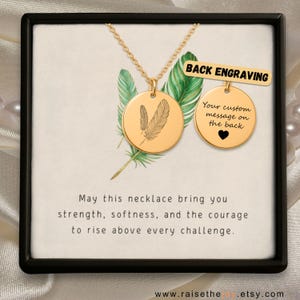 May include: Gold-colored necklace with two round pendants. One pendant features feather engravings, the other has a heart and the text "Your custom message on the back". The text "BACK ENGRAVING" is also visible. The necklace is presented in a black box.