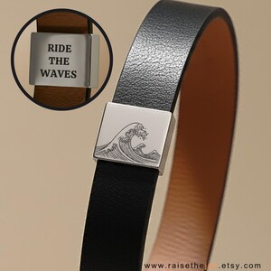 May include: Black leather bracelet with a silver square clasp featuring a wave design. A smaller inset shows a brown leather band with a silver clasp engraved with the words "RIDE THE WAVES".
