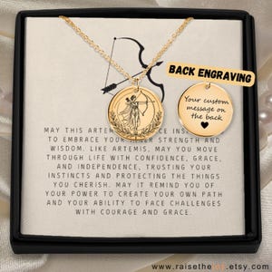 Peut inclure: Un collier doré avec un pendentif rond gravé d'une femme avec un arc et des flèches. Le collier est présenté dans un coffret noir avec le texte "Back Engraving" et "Your custom message on the back".