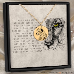 Peut inclure: Collier pendentif guépard doré. Le pendentif rond présente une illustration de guépard. Le collier est présenté dans un coffret noir avec le texte "May this cheetah necklace remind you..."