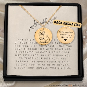 May include: Gold-colored weasel pendant necklace with a round charm. The charm features a weasel illustration and the text "Back Engraving". The necklace is presented in a black box with inspirational text.