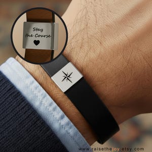 May include: A black leather bracelet with a silver clasp featuring a compass rose design. A close-up shows a brown leather bracelet with a silver clasp engraved with the words "Stay the Course" and a heart symbol.