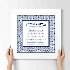 May include: A white framed print with a blue and white patterned border. The print features a Hebrew blessing for the home, "Berchat Habayit", in black text. The blessing is translated into English below the Hebrew text.