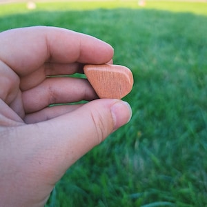 May include: A small, heart-shaped piece of wood with a light brown color and a smooth, polished finish.