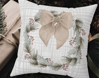 May include: A white pillow with a beige bow and a green wreath with red berries. The wreath is made of pine branches and holly leaves.
