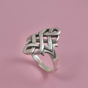 Könnte beinhalten: Ein silberner Ring mit einem keltischen Knotendesign. Der Knoten ist kompliziert und detailliert, und der Ring ist poliert.