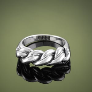May include: A silver ring with a braided design. The ring is thick and has a polished finish.