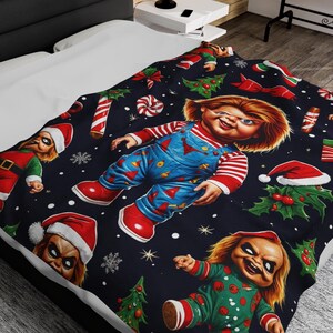 Può includere: Una coperta natalizia nera e rossa con un motivo ripetitivo di una bambola inquietante che indossa un cappello da Babbo Natale e tiene bastoncini di zucchero.