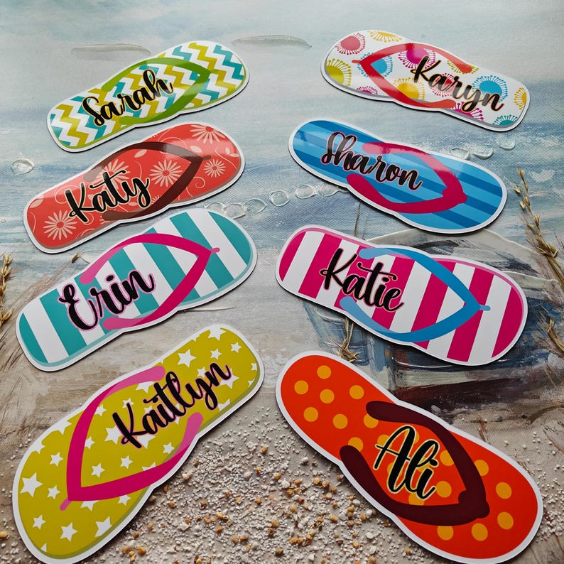 May include: A selection of personalised flip-flops with diverse patterns and names. Designs include stripes, zigzags, and floral prints in colours like green, red, blue, and yellow. Each flip-flop features a different name in a cursive font.