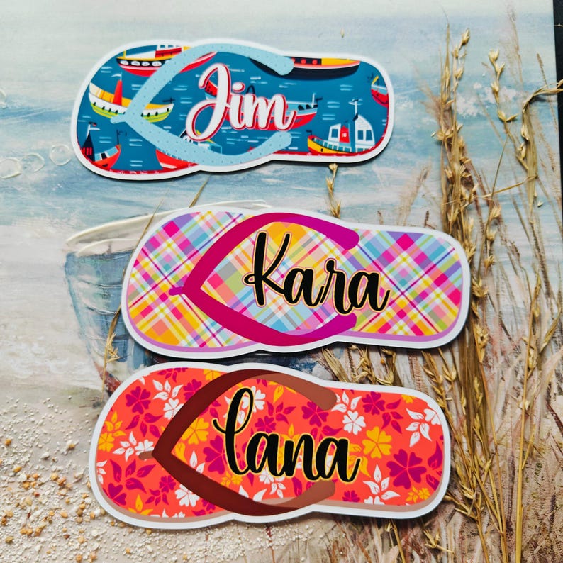 May include: Three colourful flip-flop shaped stickers with names: "Jim" on a blue nautical background, "Kara" on a plaid pattern, and "Lana" with a floral design. The stickers are designed with a beach theme.