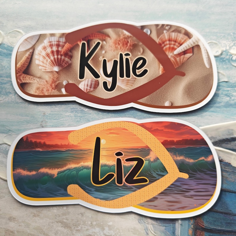 May include: Two flip-flop shaped name tags. One shows a beach scene with seashells and the name "Kylie" in black script. The other depicts a sunset over the ocean with the name "Liz" in black script.