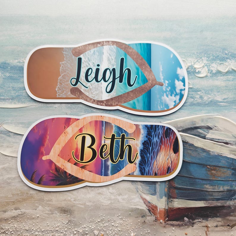May include: Two personalised flip-flop shaped stickers. One features the name "Leigh" over a beach scene with blue water and sand. The other has the name "Beth" over a sunset beach scene with palm trees.