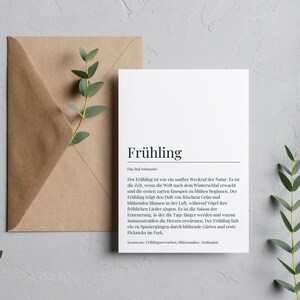 May include: A white card with the word "Fr&uuml;hling" (German for "Spring") in bold black text. The card has a definition of the word in German, describing the season as a time of renewal and growth.