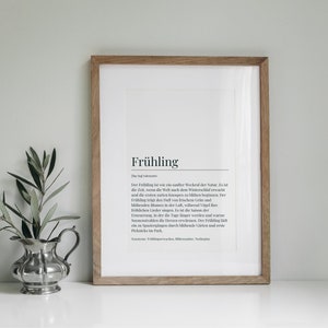 May include: A framed print with a white background and black text. The text reads "Fr&uuml;hling" which is the German word for "Spring". The text below the word "Fr&uuml;hling" is a definition of the word in German.