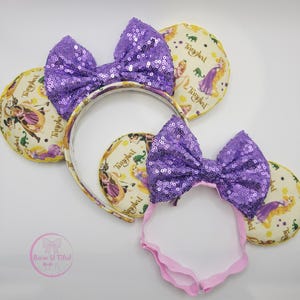 May include: Three headbands with purple sequin bows and round ears. The ears feature a cartoon princess and the word "Tangled". The headband is white and the ears are yellow.