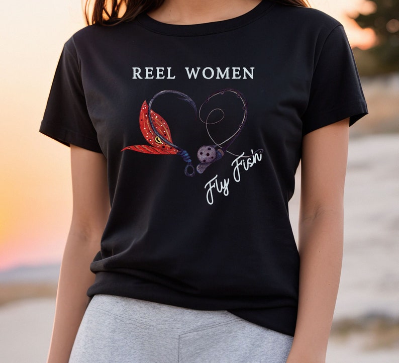 May include: Black t-shirt with the text "Reel Women Fly Fish'n" in white. The text is surrounded by a heart shape made of a fishing hook and a fly.