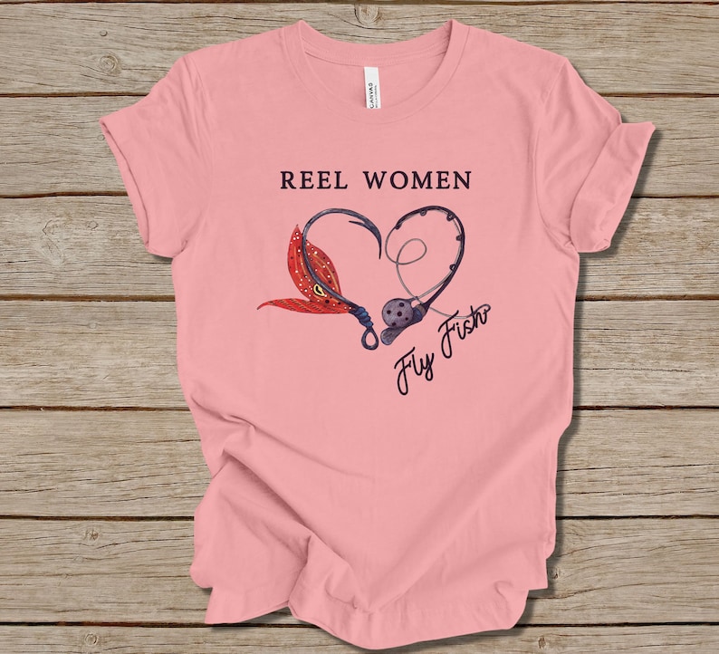 May include: Pink t-shirt with the text "Reel Women Fly Fish" and a graphic of two fishing hooks forming a heart shape with a fly on one hook.