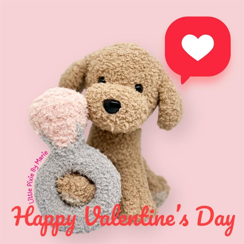 May include: A brown plush dog toy holding a pink and gray ring toy. The dog is sitting on a pink background with a red speech bubble with a white heart in it. The text "Happy Valentine's Day" is written in red below the dog.