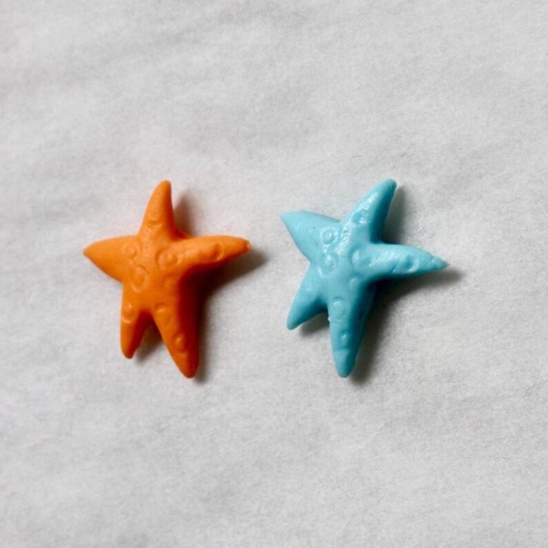 May include: Two starfish, one orange and one blue, on a white background.