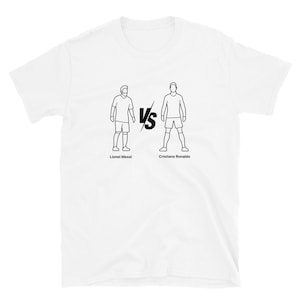 May include: White t-shirt featuring a black line drawing of two soccer players facing each other, separated by a "VS" symbol. The names "Lionel Messi" and "Cristiano Ronaldo" are printed below the figures.