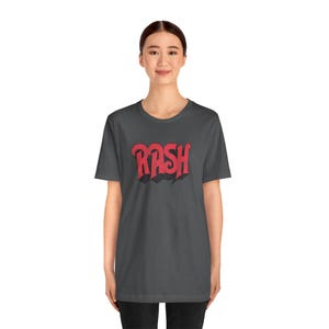 May include: A dark gray t-shirt with a red graphic of the word "RASH" in a stylized font.