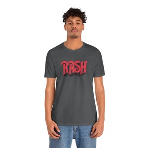 May include: A dark gray t-shirt with a red graphic of the word "RASH" in a stylized font.