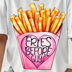 May include: White t-shirt with a graphic of a pink heart-shaped box of french fries. The text on the box reads "Fries Before Guys".