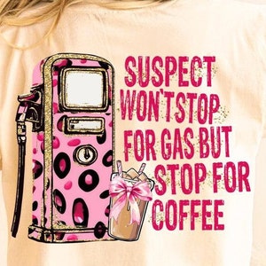 May include: A white t-shirt with a pink and gold gas pump and a pink and brown coffee cup graphic. The text on the shirt reads "Suspect won't stop for gas but stop for coffee".