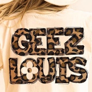 May include: White t-shirt with a brown and black leopard print graphic that says "Geez Louis" on the back.