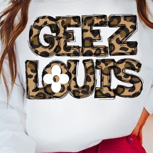 May include: White sweatshirt with a leopard print design that says "Geez Louis" with a white flower in the middle of the word "Louis".