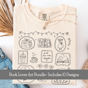 May include: A cream-colored t-shirt featuring a black line art graphic of books, a goose wearing glasses, a coffee cup, a drink, and the text "just one more chapter" inside decorative frames, with a string of lights and bows above the designs.