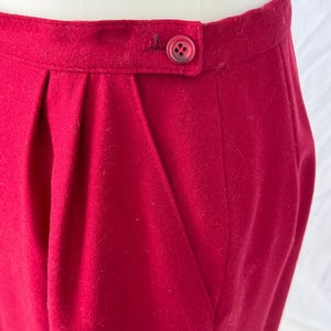 May include: A close-up of a red skirt with a single button at the waist.
